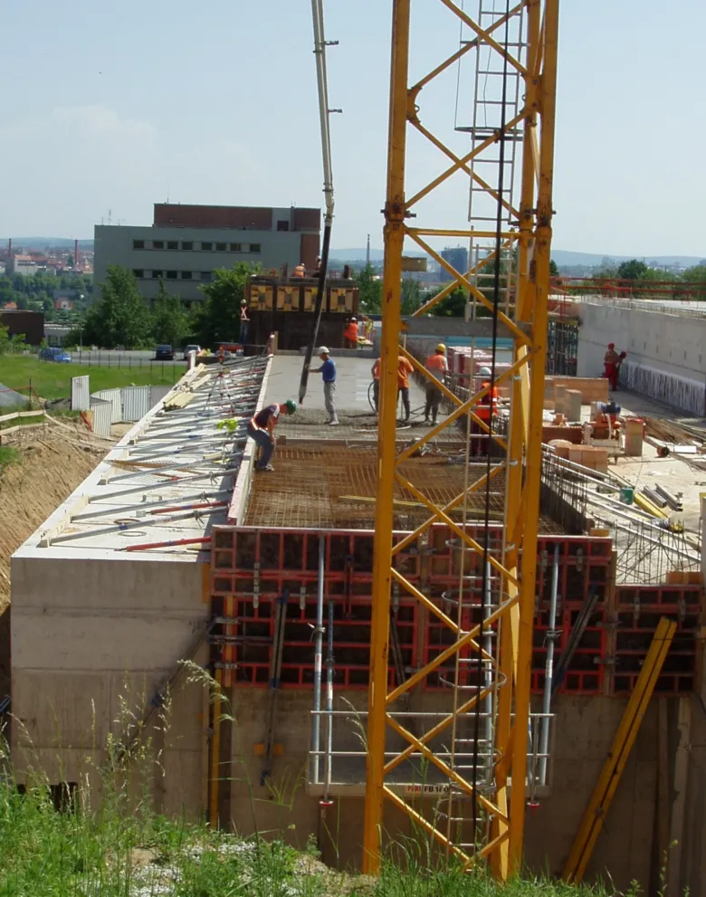 Stavební dělníci nalévají beton na staveništi s žebry a tvary.
