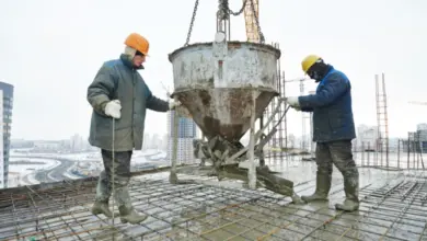 Dva dělníci nalévají beton na výztuž v zimě.