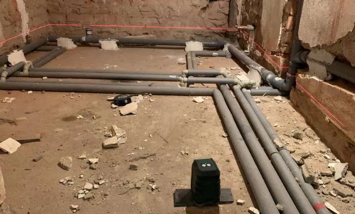 Instalace potrubí pro izolaci podlahy v koupelně před dlažbou.