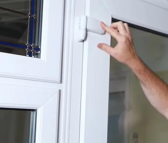 Ruka nastavuje výšku plastového okna pomocí šroubováku.