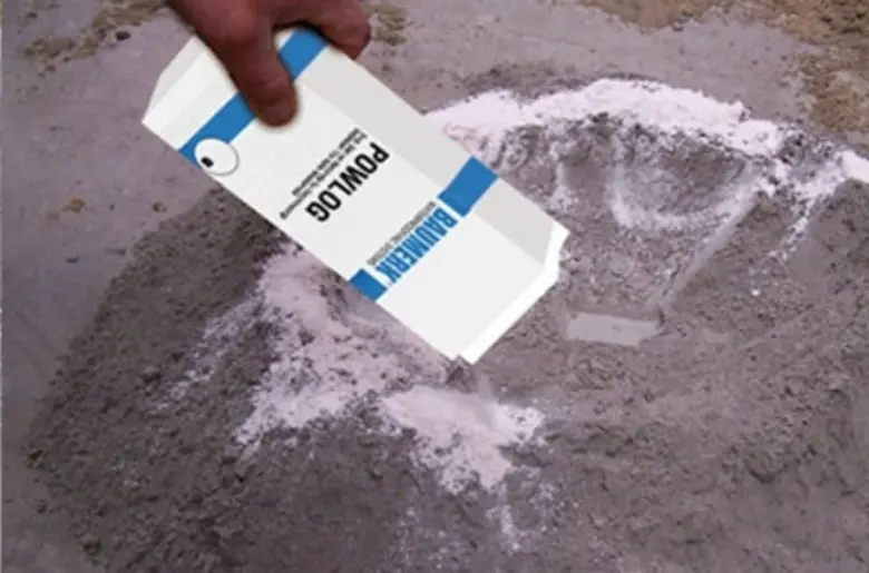 Rozprašování bílého prášku na beton pro zajištění vodotěsnosti.