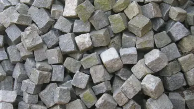 Hromada šedých a zelenavých žulových dlažebních kostek.