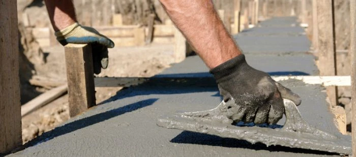 Stavebník hladí čerstvý beton v bednění před jeho odstraněním.