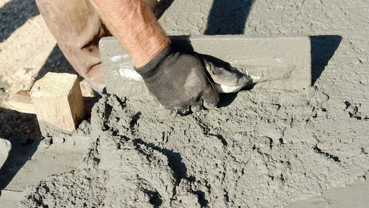 Ruční hladění čerstvého betonu špachtlí na stavbě.