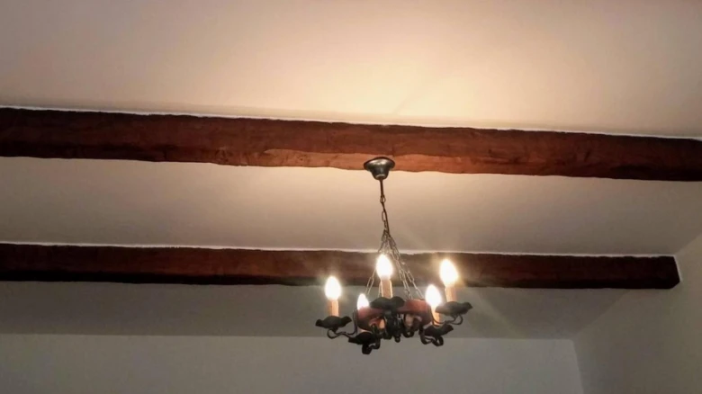 Falešné dřevěné trámy na strop s lustry mezi nimi.
