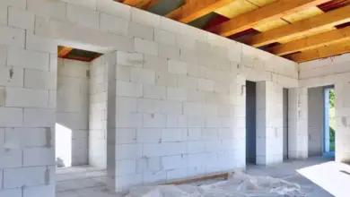 Nezhotovený interiér s viditelnými trámy stropu a blokovými zdmi.