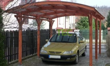 Dřevěný přístřešek pro auto s žlutým autem zaparkovaným pod ním na dlažbě vedle plotu