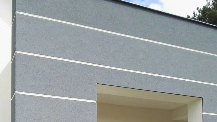 Moderní fasáda s horizontálními bílými pruhy nad vchodem.