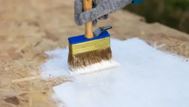 Ruční maření OSB desky bílou ochrannou vrstvou venku.