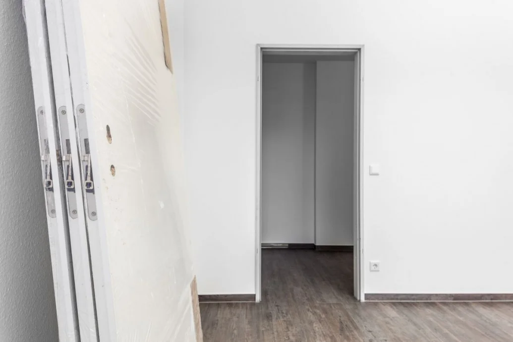 Nová bílá vnitřní dveře leží u zdi vedle otvoru pro montáž