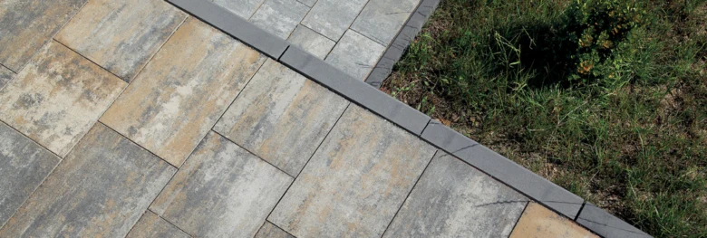 Nově položený obrubník z tmavých kamenů vedle trávníku