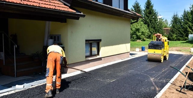 Práce na asfaltu před domem s parní válcovnou.