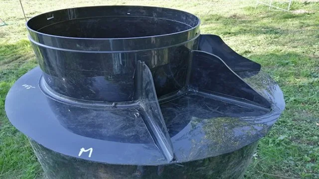 Černý plastový prstenec pro obložení studny ležící na trávě.
