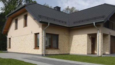 Dokončený štít domu s obkladem na pozadí trávníku.