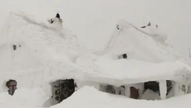 Tradiční dům s hřebenovou střechou pokrytou silnou vrstvou sněhu.