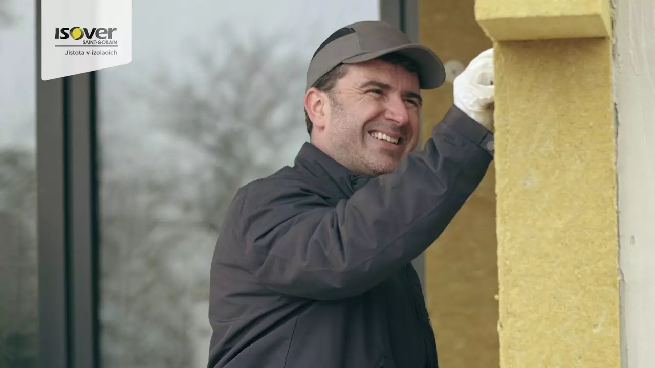 Stavebník aplikuje minerální vatu na fasádu při zateplování.