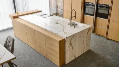 Moderní kuchyňská ostrov s mramorovou deskou a dřevěnými skříněmi.