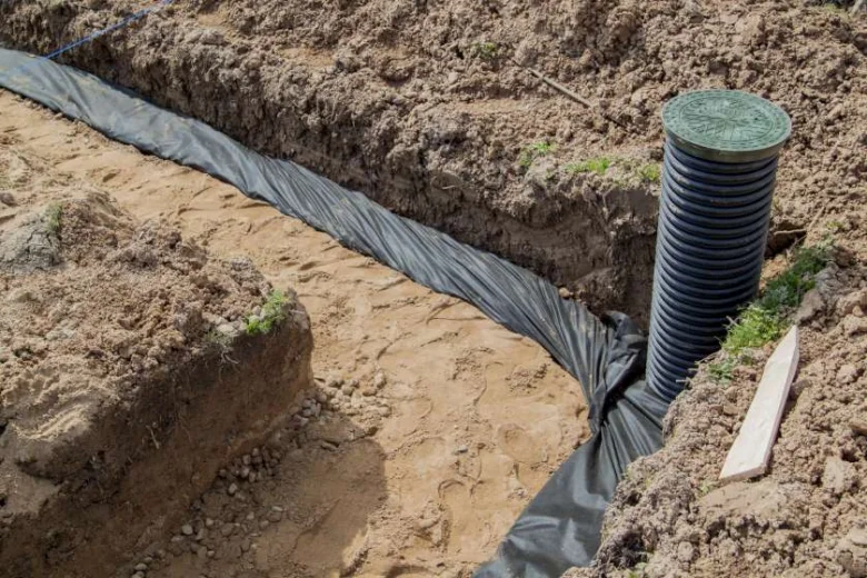 Instalace drenážní trubice v příkopu s textilním filtrem.