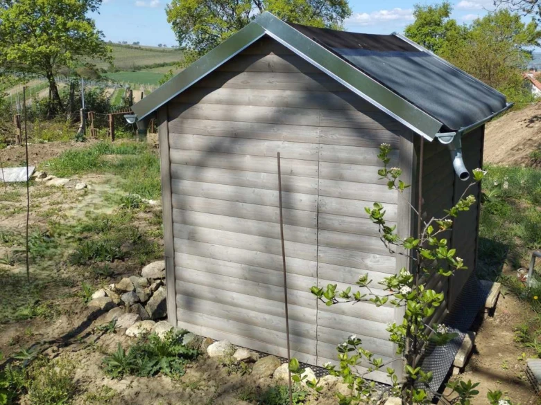 Dřevěná kůlna v zahradě ukazuje typickou stavbu pro regulaci vzdálenosti od sousedních pozemků.