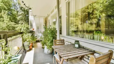 Dřevěný balkon s nábytkem a rostlinami v přírodním prostředí.