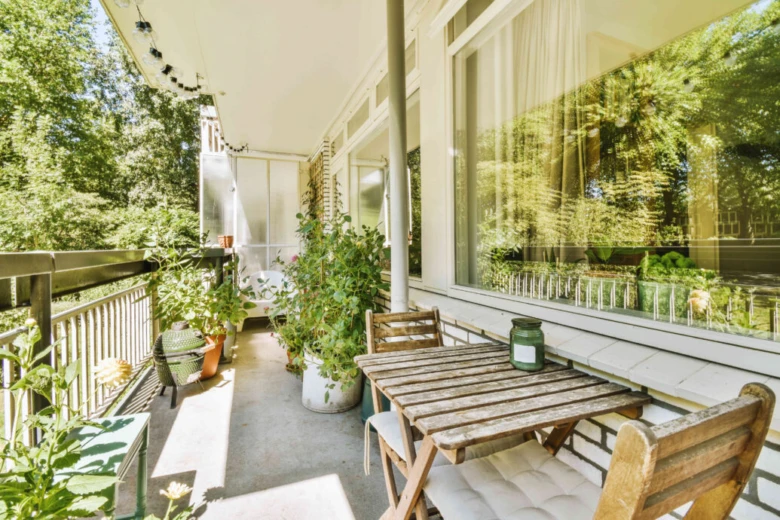 Dřevěný balkon s nábytkem a rostlinami v přírodním prostředí.
