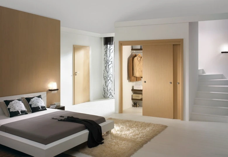 Moderní ložnice s posuvnými dřevěnými dveřmi do šatny.