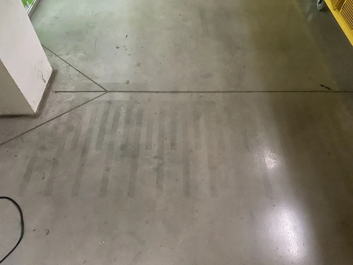 Betonová podlaha s viditelnými dilatačními spárami u stěny.