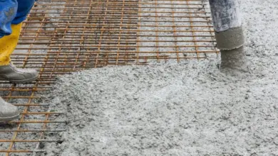 Zaměstnanec nalévá čerstvý beton na ocelovou výztuž.