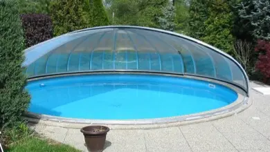 Kruhový bazén s průhlednou kopulí v zahradě.