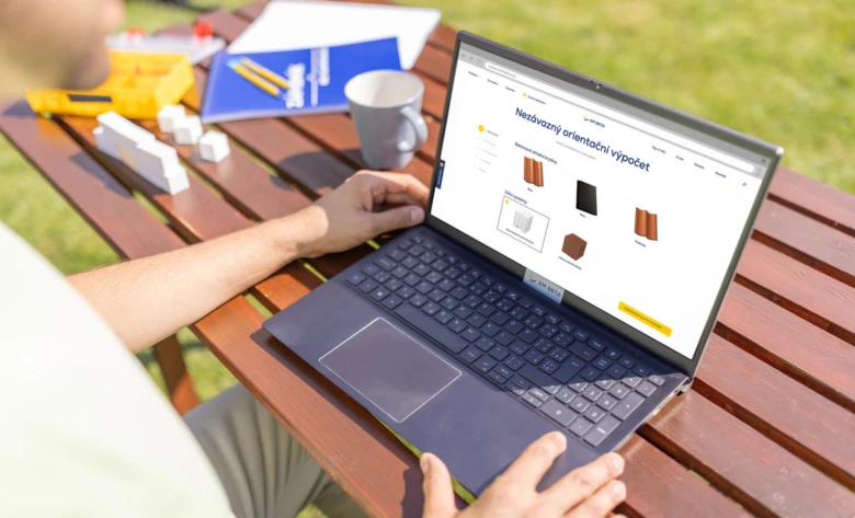 Muž počítá množství stavebního materiálu na notebooku venku.