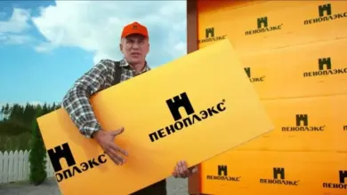 Muž drží žlutou desku izolace Penoplex venku.