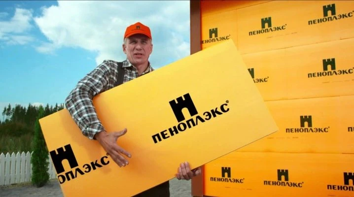 Muž drží žlutou desku izolace Penoplex venku.