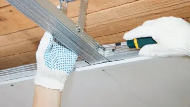Ruční instalace kovového profilu pro sádrokarton na dřevěné trámy.