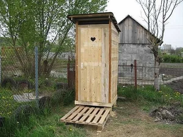 Samostatná dřevěná venkovní záchodová budova postavená ze palet.