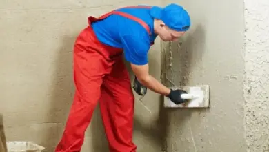 Stavebník nanáší omítku na stěnu pomocí špachtle.