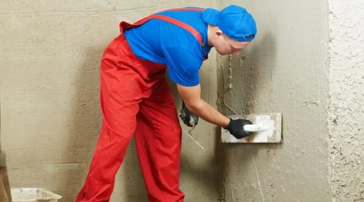 Stavebník nanáší omítku na stěnu pomocí špachtle.