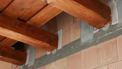 Dřevěný trám připevněný k cihlové zdi pomocí maltových bloků.