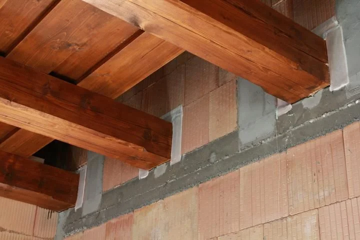 Dřevěný trám připevněný k cihlové zdi pomocí maltových bloků.