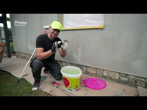 Muž nanáší omítku na fasádu stavebního materiálu.