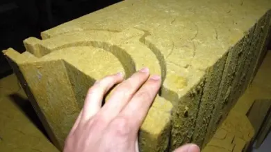 Ruka drží žlutý izolovaný cihlový blok pro komínovou trubku.