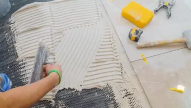 Náplast na dlažbu se nanáší špachtlí před položením keramiky.