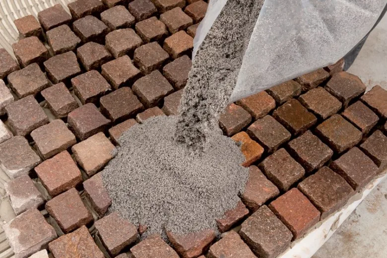 Nalévání špičkového materiálu do spár dlažebních kostek.