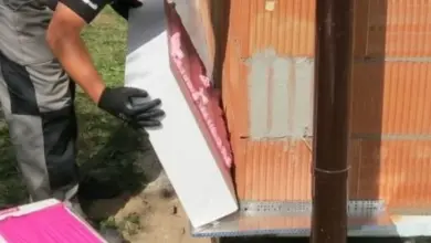 Montážní pracovník připevňuje panel z expandovaného polystyrénu na kovovou stěnu.