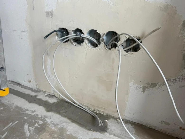 Vrtané otvory v panelové stěně pro elektrické rozvody.