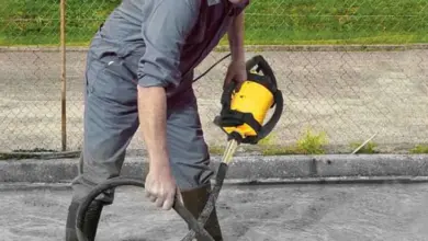 Muž vibruje čerstvý beton žlutým vibračním nástrojem.