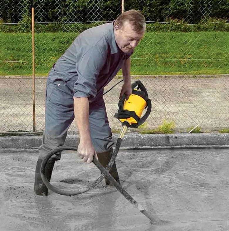 Muž vibruje čerstvý beton žlutým vibračním nástrojem.