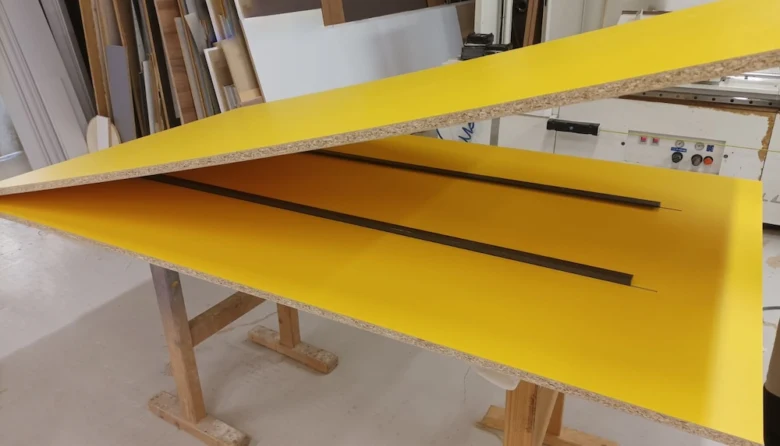 Žlutá laminátová deska na pilovém stole v dílně