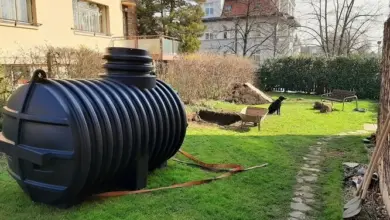 Černá plastová nádrž na zahradě vedle domu.