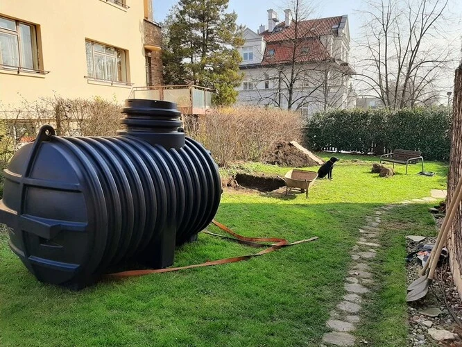 Černá plastová nádrž na zahradě vedle domu.