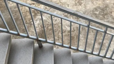 Schodiště s betonovými schody a kovovým zábradlím na dlažbě.